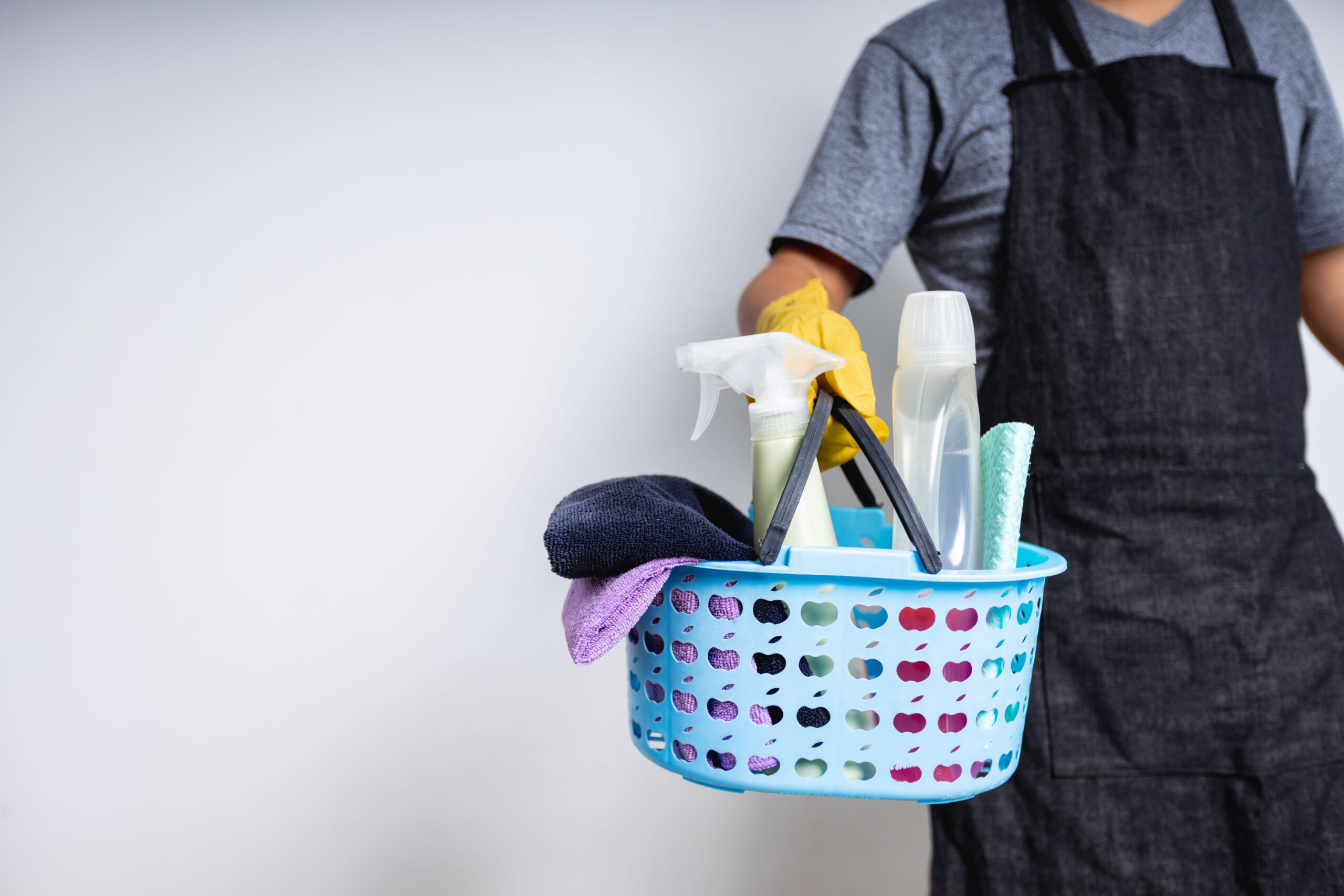 Man janitor holding basket of cleaning supplies preparing to clean at house